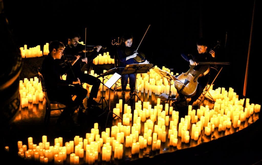 string quartet on stage surrounded by heaps of candles
