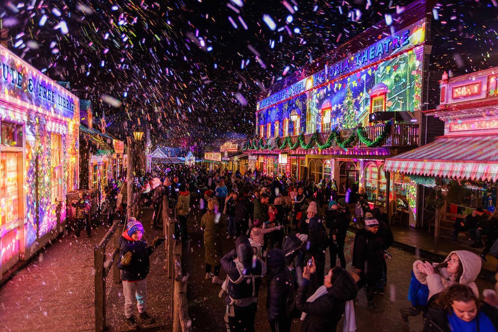 people looking at projections underneath falling snow at Winter Wonderlights